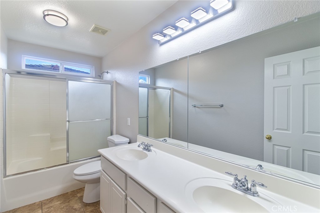 46321 Sharon Street Temecula, CA 92592 - Photo 25 of 40 a bathroom with a toilet a sink a mirror and a shower