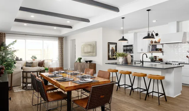 a dining room with stainless steel appliances kitchen island granite countertop a dining table chairs and a refrigerator