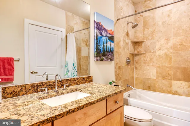 a bathroom with a granite countertop sink and a bathtub