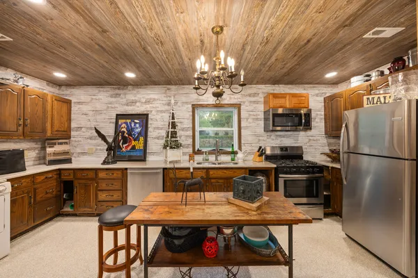 a kitchen with stainless steel appliances granite countertop a refrigerator a sink dishwasher a dining table and chairs with wooden floor