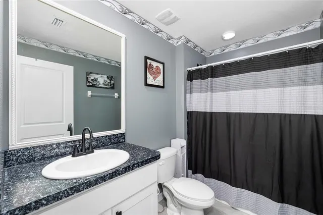 a bathroom with a granite countertop sink vanity mirror and toilet