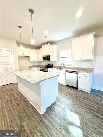 a kitchen with stainless steel appliances granite countertop a sink a stove a refrigerator cabinets and chairs