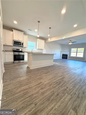 a view of kitchen with kitchen island wooden floor and stainless steel appliances