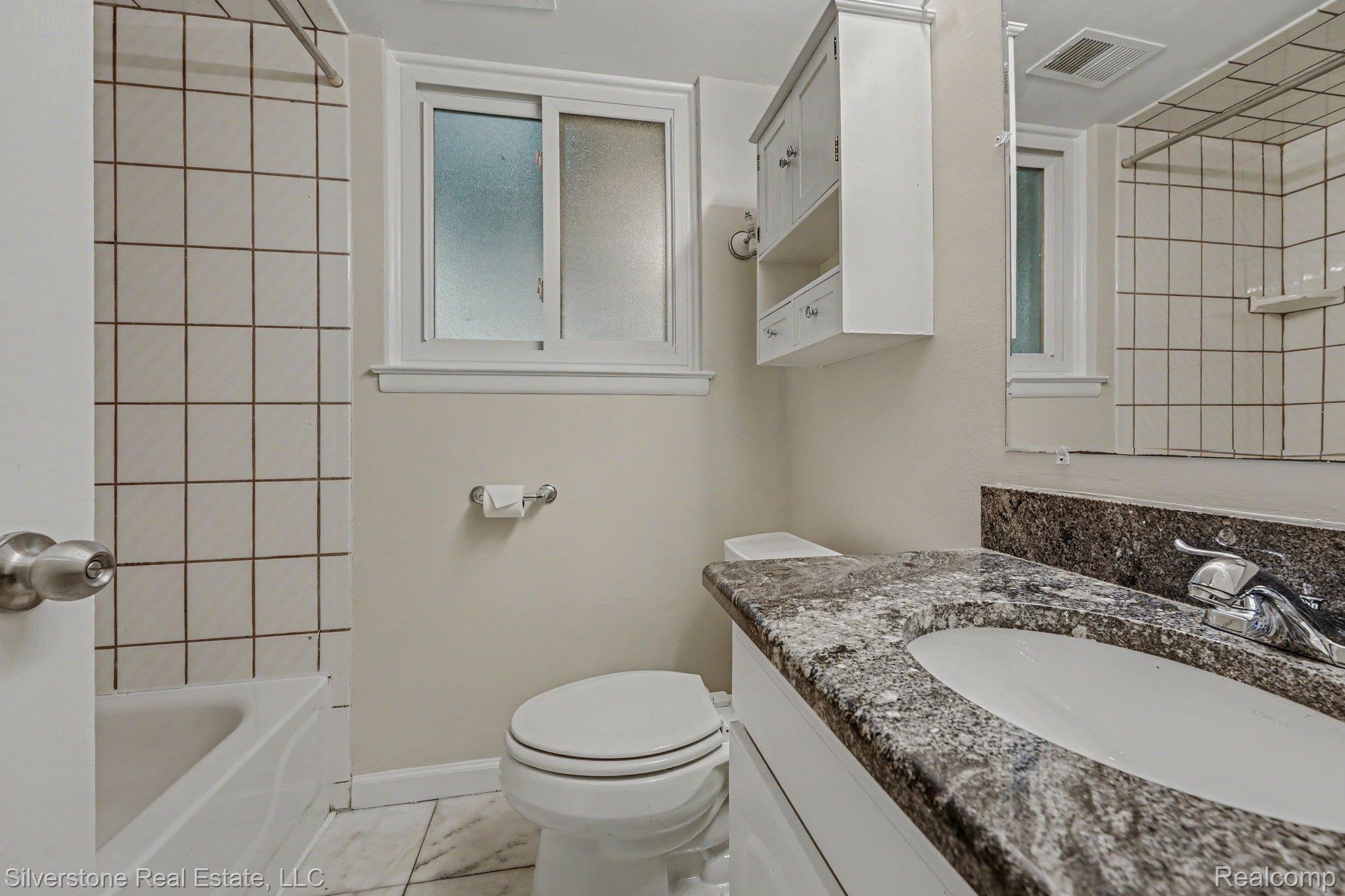 547 Reed Street Northville, MI 48167 - Photo 26 of 38 Bathroom featuring a white vanity with a dark speckled countertop, an undermount sink, and a chrome faucet