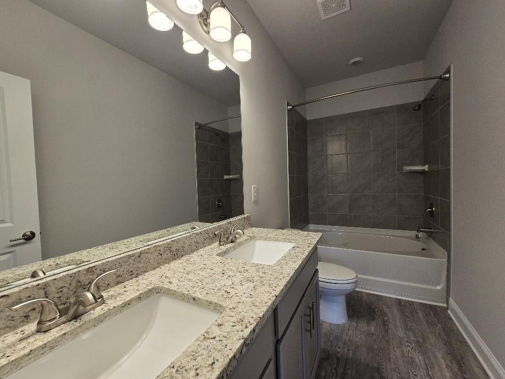 6206 Ripple Way, Unit 89 Atlanta, GA 30349 - Photo 21 of 26 a bathroom with a granite countertop sink a toilet and bathtub