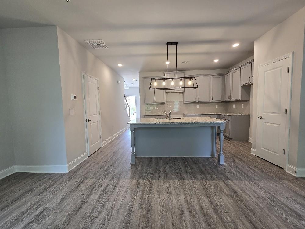 6206 Ripple Way, Unit 89 Atlanta, GA 30349 - Photo 6 of 26 a kitchen with kitchen island stainless steel appliances a dining table chairs and wooden floor