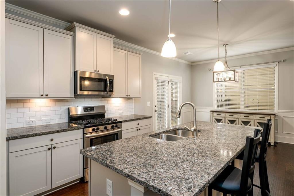 6622 Trailblazer Road Flowery Branch, GA 30542 - Photo 14 of 51 a kitchen with granite countertop a stove a sink dishwasher a microwave oven with granite countertops and cabinets