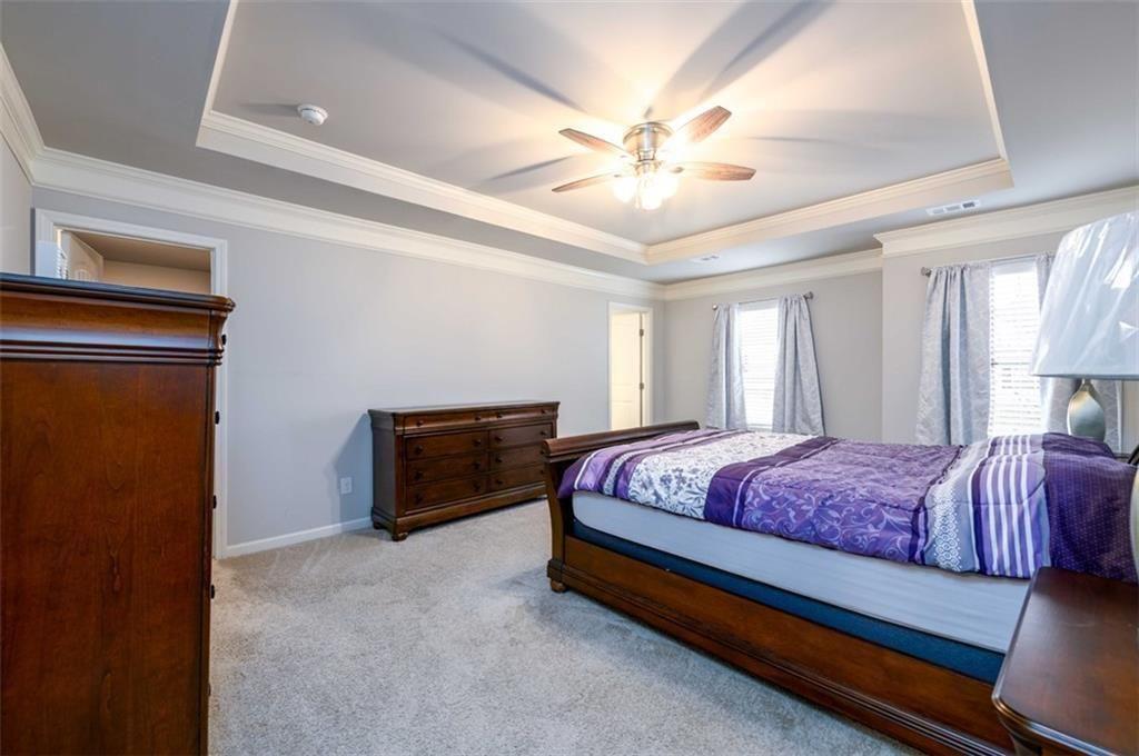 6622 Trailblazer Road Flowery Branch, GA 30542 - Photo 21 of 51 a spacious bedroom with a bed and a chandelier