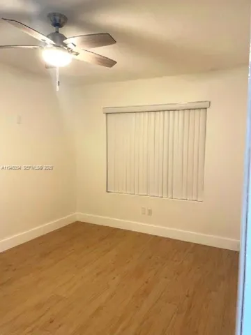 an empty room with wooden floor and fan