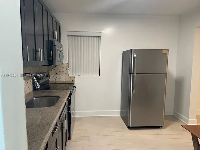 a kitchen with a refrigerator sink and cabinets