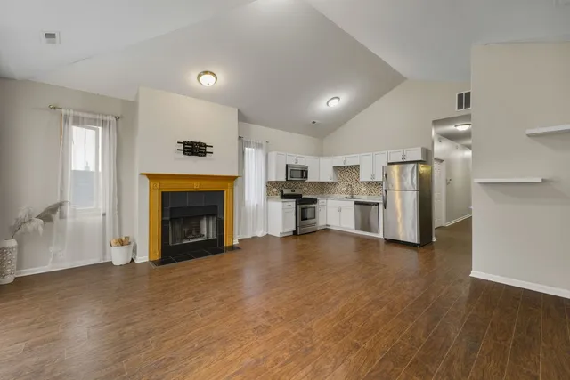 a view of a kitchen with a refrigerator a stove top oven cabinets and wooden floor