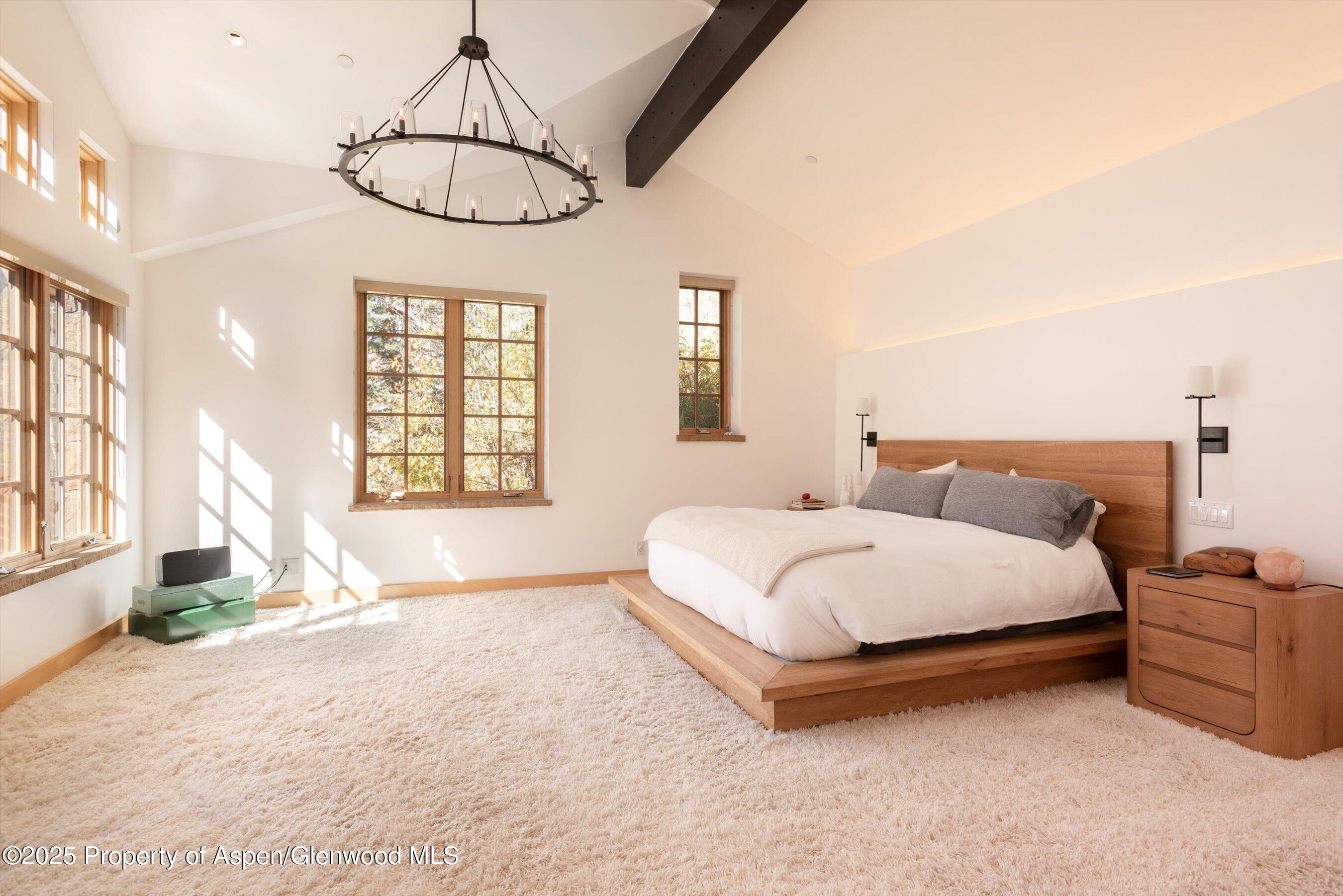 6770 Castle Creek Road Aspen, CO 81612 - Photo 17 of 53 a spacious bedroom with a bed a chandelier and large window