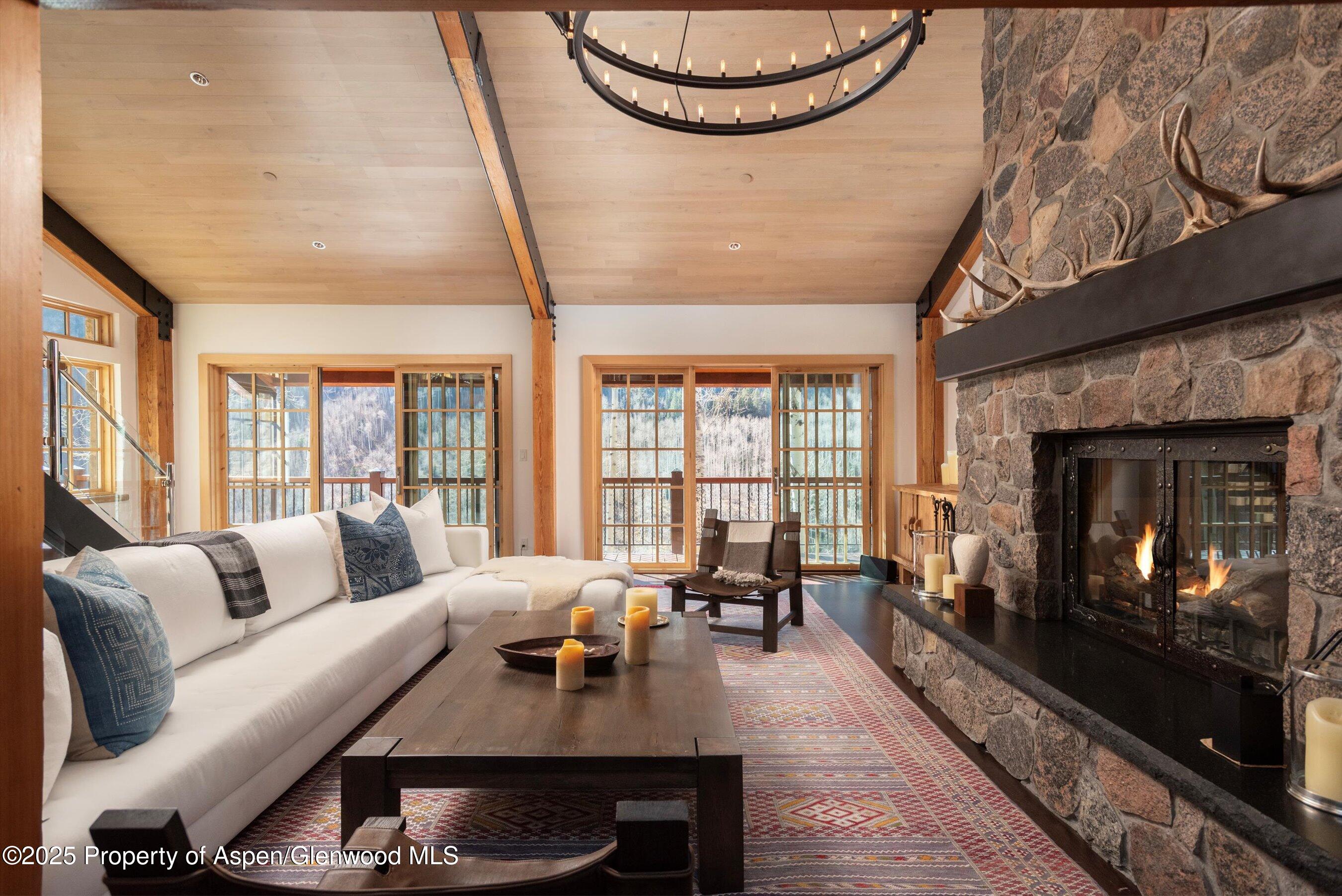 6770 Castle Creek Road Aspen, CO 81612 - Photo 8 of 53 a living room with furniture a fireplace and a floor to ceiling window