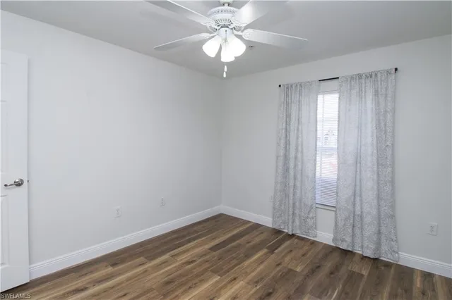 a view of an empty room with window chandelier fan