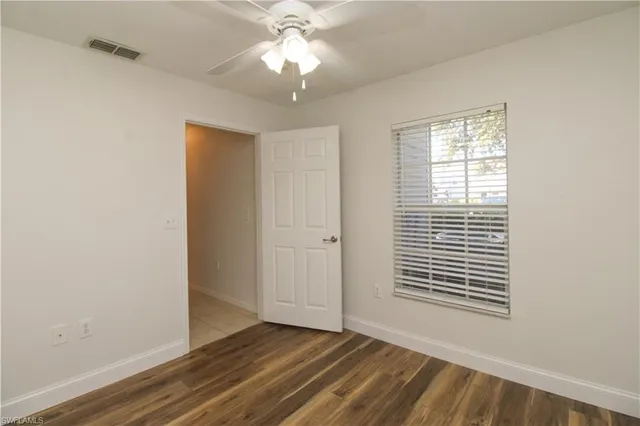 a view of an empty room with a window and wooden floor