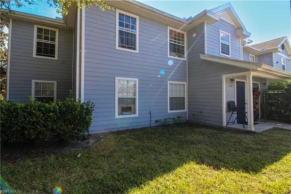 a view of a brick house with a yard potted plants and a table and chair