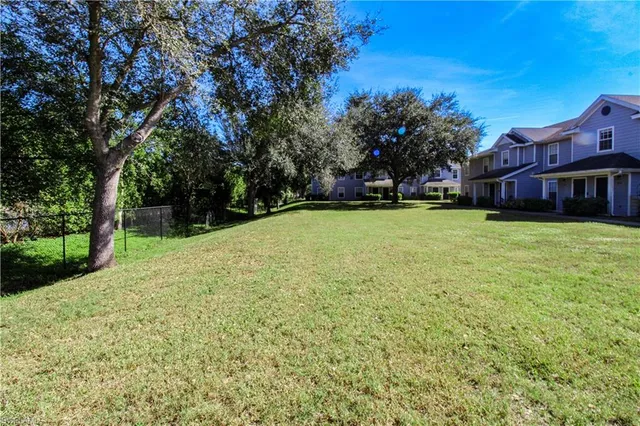a view of a green field with trees in front of it