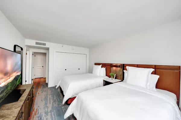 a bedroom with two beds and a flat screen tv