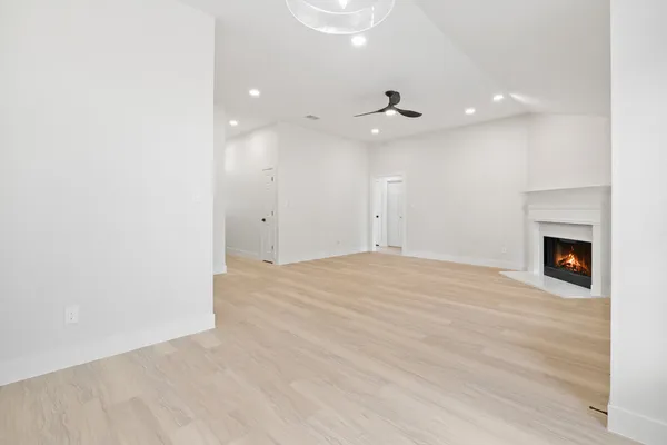 an empty room with wooden floor a ceiling fan and a fireplace
