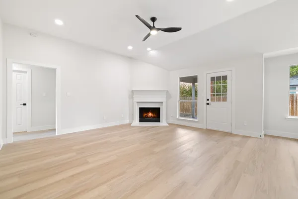 a view of an empty room with wooden floor fireplace and a window