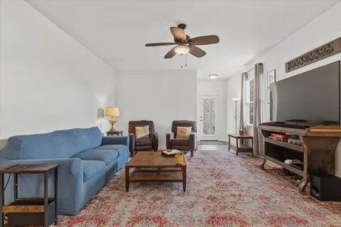 a living room with furniture a ceiling fan and a rug