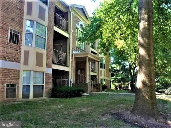 a view of a brick house with a yard and large trees