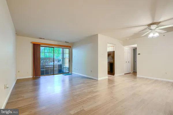 a view of an empty room with window and wooden floor