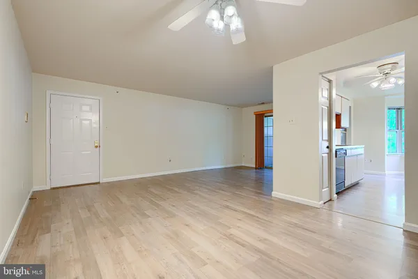 an empty room with kitchen view and wooden floor