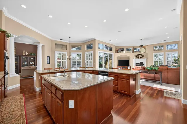 a kitchen with stainless steel appliances a dining table chairs and wooden floor
