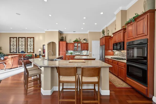 a kitchen with stainless steel appliances granite countertop a stove a refrigerator a sink and dishwasher with wooden floor