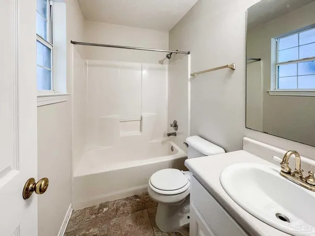 en empty room with windows and ceiling fan