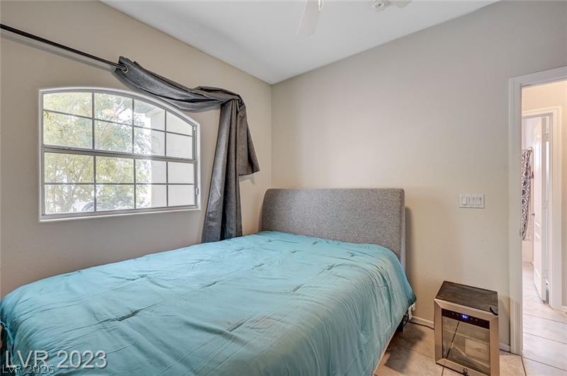 987 Cutter Street Henderson, NV 89011 - Photo 15 of 17 A well-lit bedroom with a ceiling fan, featuring a window overlooking natural greenery.