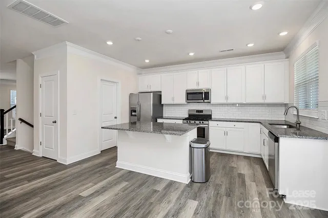 a kitchen with granite countertop a sink cabinets and stainless steel appliances
