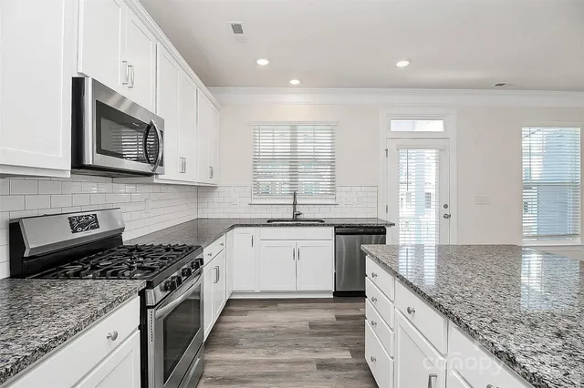 a large kitchen with stainless steel appliances granite countertop a stove and a sink