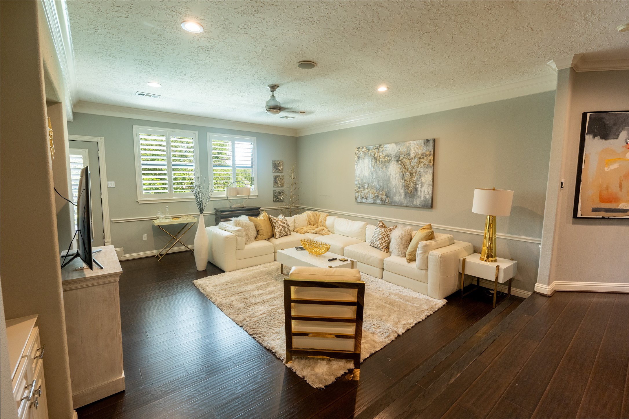 4002 Silver Ridge Boulevard Missouri City, TX 77459 - Photo 27 of 50 This is a modern and elegantly decorated (sunken) upstairs Gameroom room featuring dark hardwood floors, neutral wall colors with white trim, plantation shutters on the windows, and a textured ceiling with recessed lighting. It offers a comfortable and chic space for relaxation and entertainment.