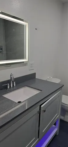 a white toilet sitting next to a bathroom sink and vanity
