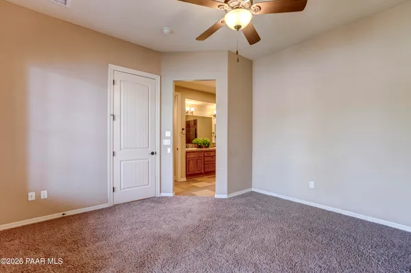 an empty room with a chandelier fan and a bathroom