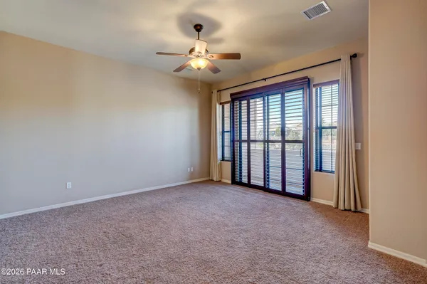 a view of an empty room with chandelier fan