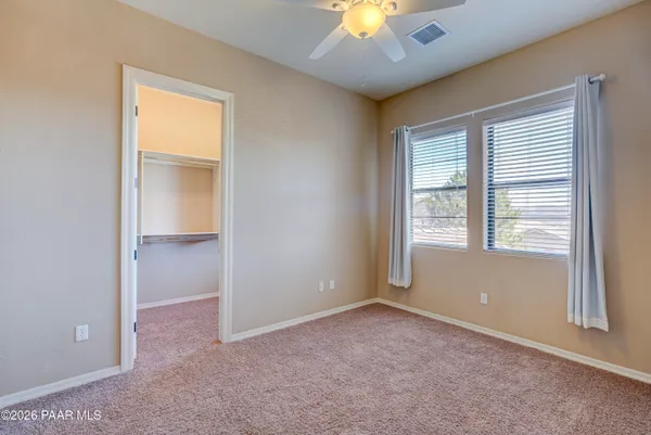 an empty room with a chandelier fan and a window