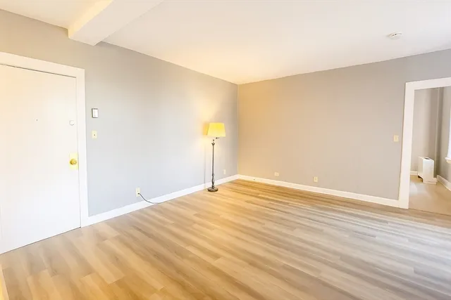 a view of empty room with wooden floor and windows