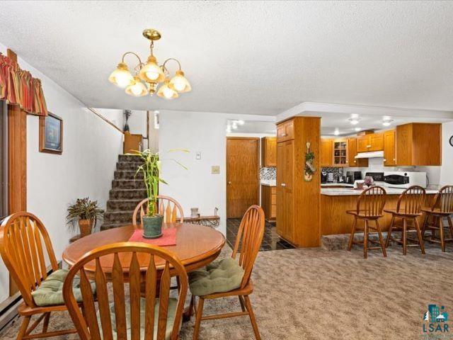 3616 Lavaque Road Hermantown, MN 55811 - Photo 2 of 43 Open-concept living space featuring a carpeted main area, a kitchen with wood cabinetry and a breakfast bar, and a visible staircase
