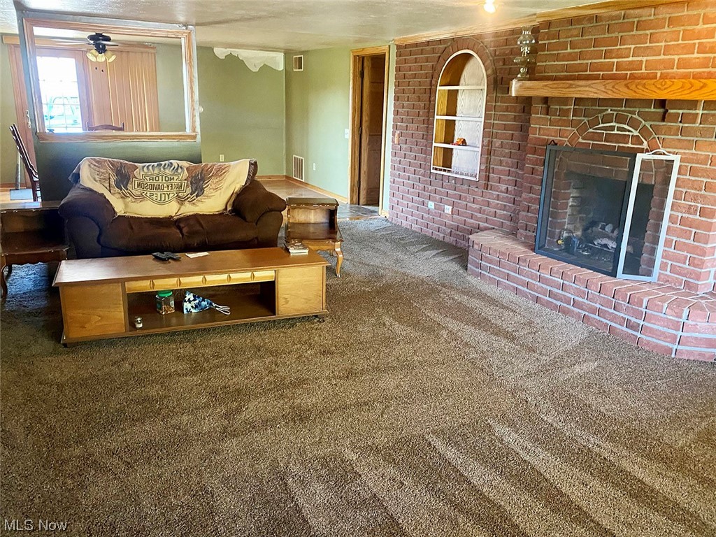 11043 Lippincott Road East Rochester, OH 44625 - Photo 28 of 34 Living room with a fireplace, ceiling fan, carpet, brick wall, and a textured ceiling