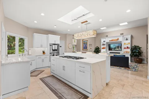 a large white kitchen with a large window and stainless steel appliances