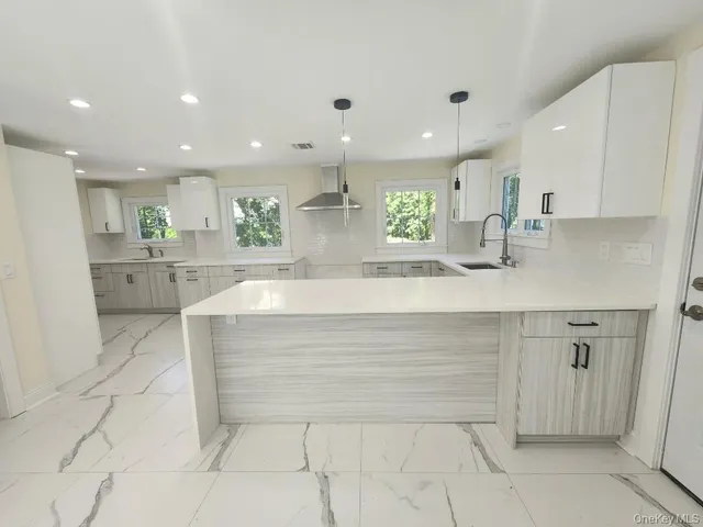 a large white kitchen with kitchen island a sink a stove a refrigerator and white cabinets