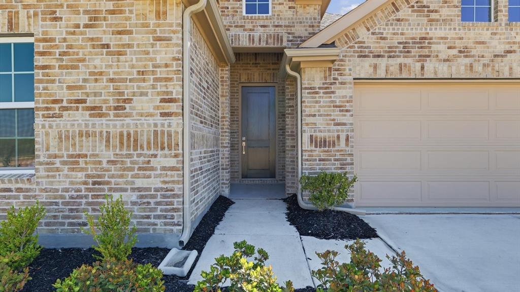 2529 Rivers W Road Anna, TX 75409 - Photo 7 of 40 Brick exterior featuring a two-car garage, covered entry, front door, and mature landscaping