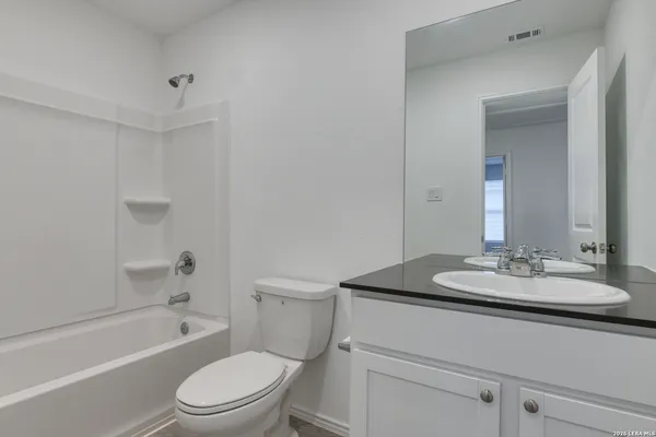 a bathroom with a granite countertop sink toilet a mirror and shower