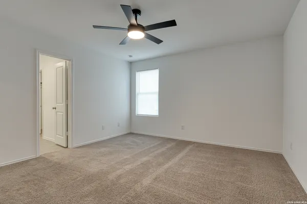 an empty room with a chandelier fan and windows