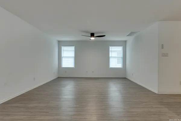 an empty room with wooden floor and windows