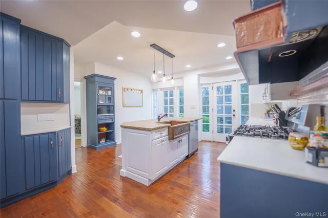 a large kitchen with stainless steel appliances a large counter top a stove and a wooden floors