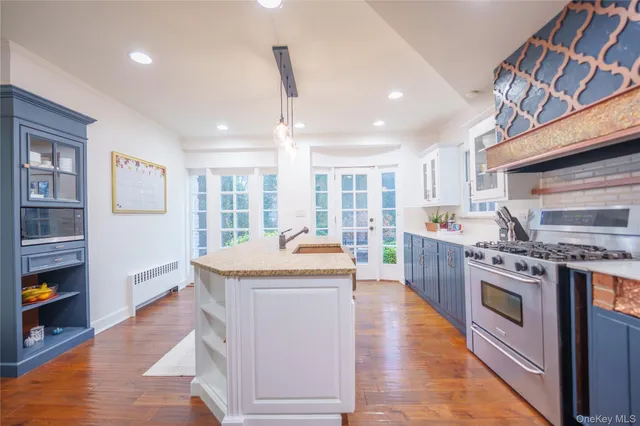 a kitchen with stainless steel appliances granite countertop a sink a stove and a wooden floors